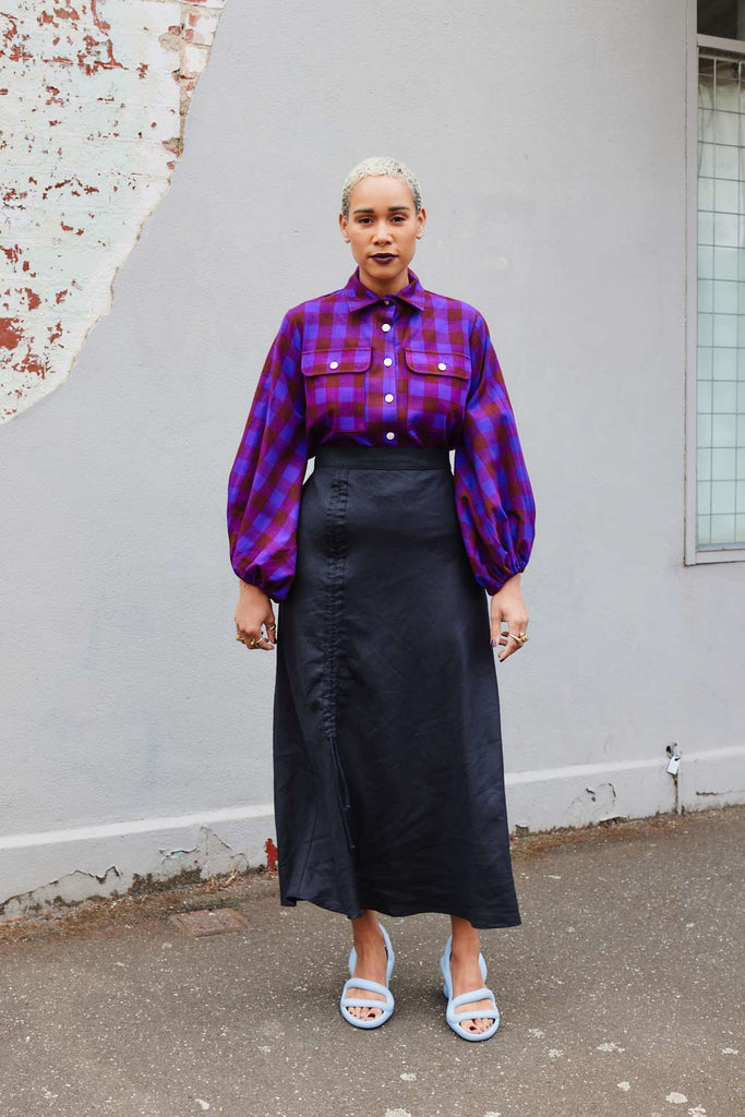 Collective Closets model wears high waisted skirt and purple shirt