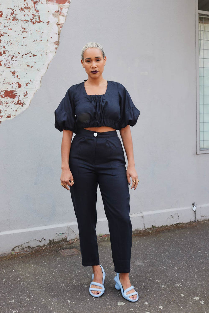 Collective Closets model in high waisted pants and crop top in black linen